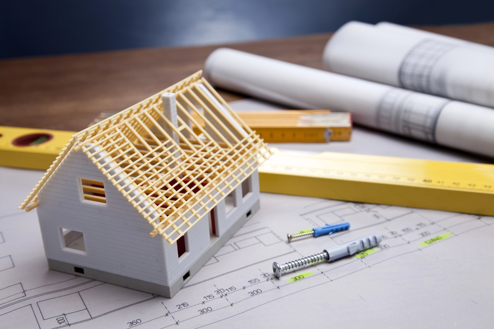 Model domu z więźbą dachową na projekcie budowlanym z narzędziami pomiarowymi